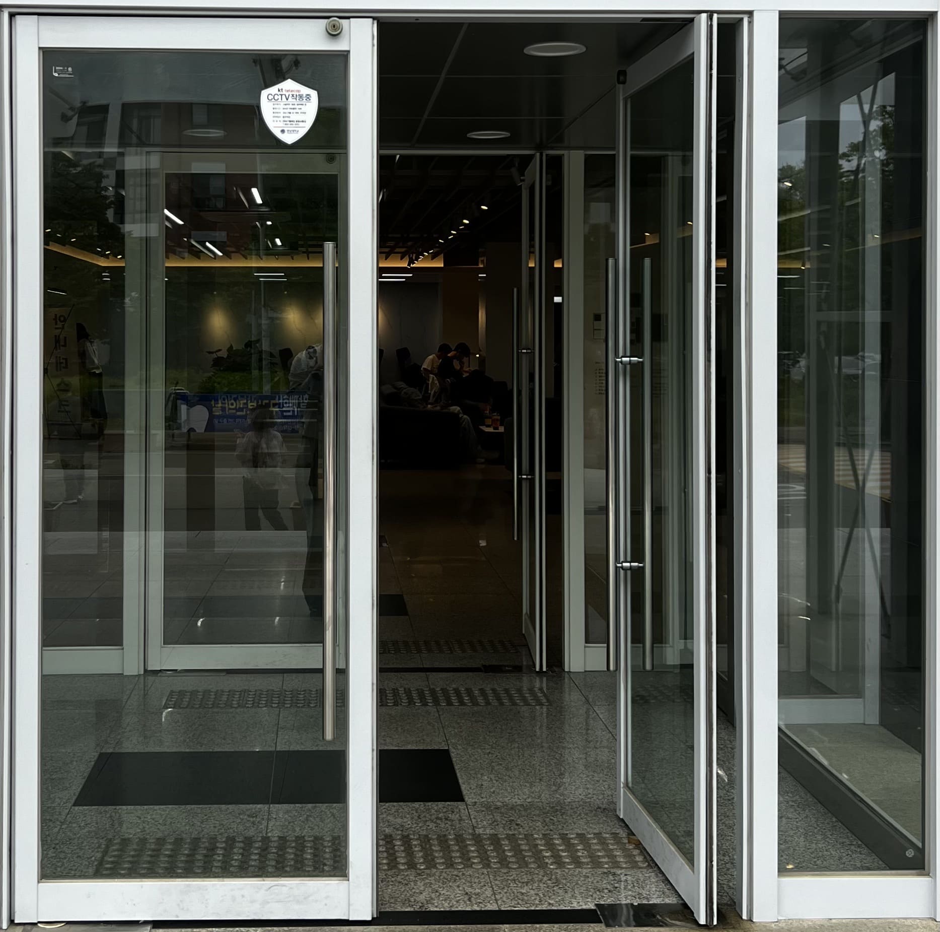 흰색 테두리를 가진 투명문이다. 왼쪽 문은 닫혀있고 오른쪽 문은 열려있다.